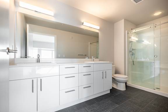A modern bathroom with a large mirror, sink, and walk-in shower.
