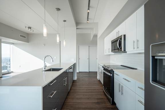 A modern kitchen with white cabinets and a wooden floor.