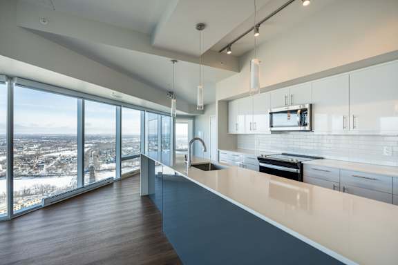 A modern kitchen with a large island and a view of the city.