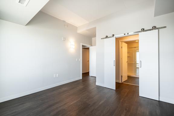 A room with white walls and wood flooring with a sliding door.