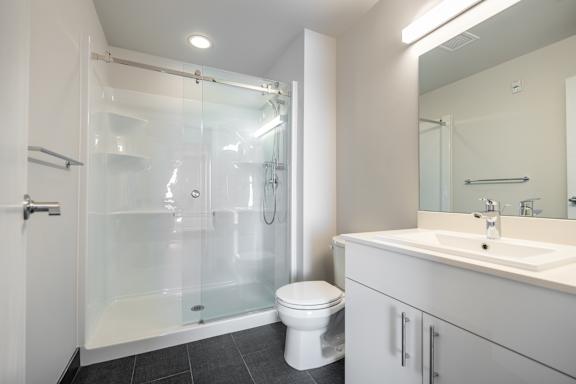 A white toilet sits in a bathroom next to a sink.