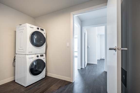 A white washing machine is stacked on top of another white washing machine in a room.