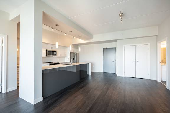 A modern kitchen with dark wood floors and white walls.