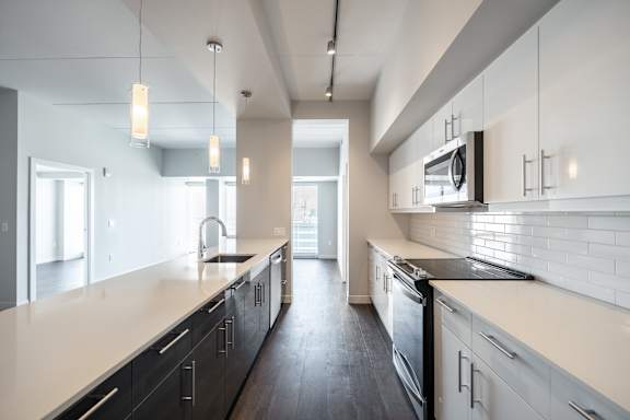 A modern kitchen with black and white cabinets and a black stove top oven.