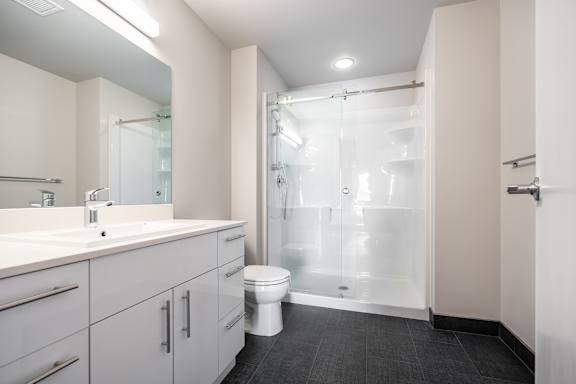 A white bathroom with a toilet, sink, and shower.