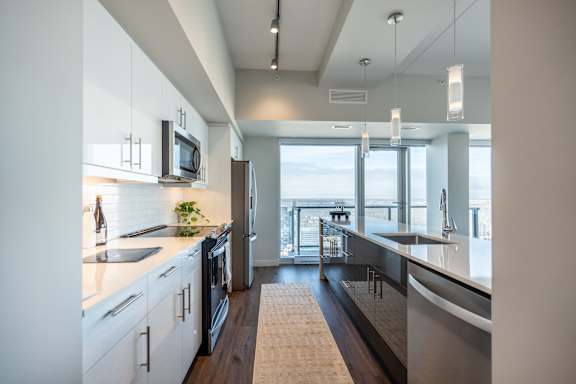 A modern kitchen with white cabinets and a view of the city.