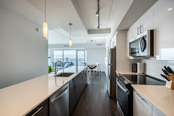 A modern kitchen with a long counter and stainless steel appliances.