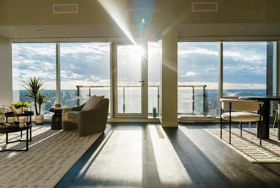A sunny day at the beach is visible through the windows of a modern living room.