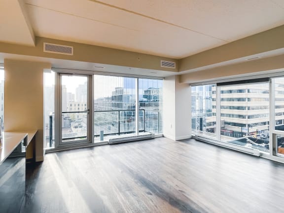 an empty living room with large windows and a view of the city