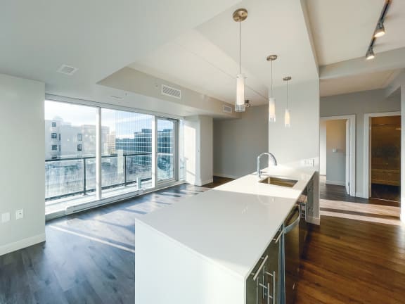 a kitchen with white countertops and a large window with a view of the city