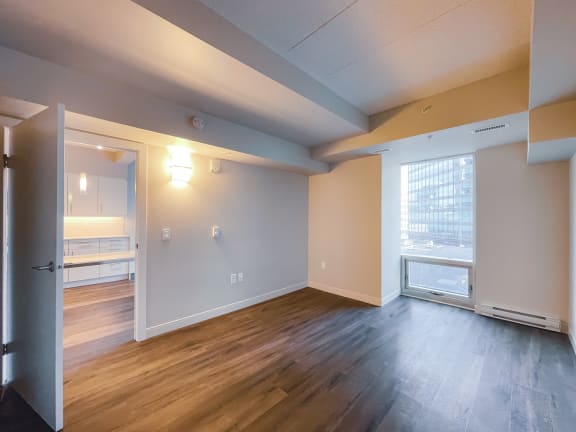 an empty living room with hardwood floors and a large window