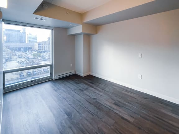 a bedroom with hardwood floors and a large window