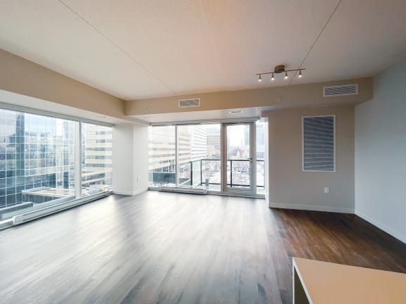 an empty living room with hardwood floors and a balcony