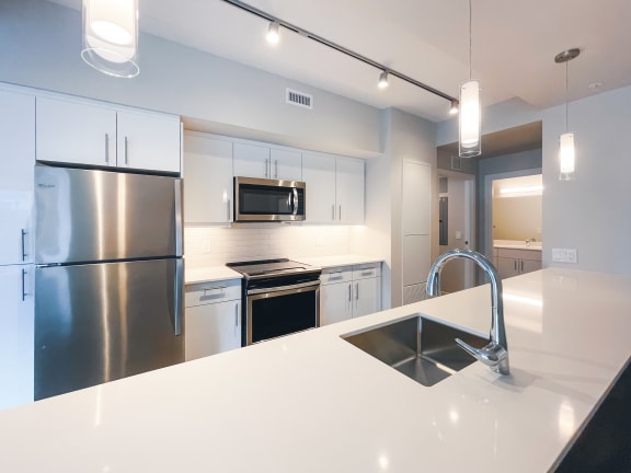 a kitchen with white countertops and stainless steel appliances