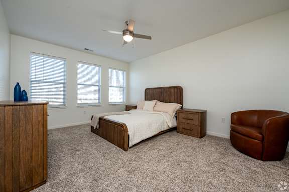 A bedroom with a bed, chair, and a dresser.