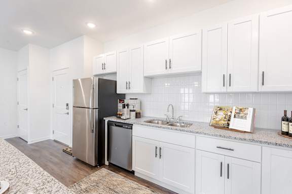 A kitchen with white cabinets and a stainless steel refrigerator.