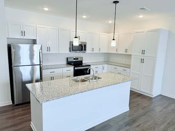 A kitchen with a granite countertop and stainless steel appliances.