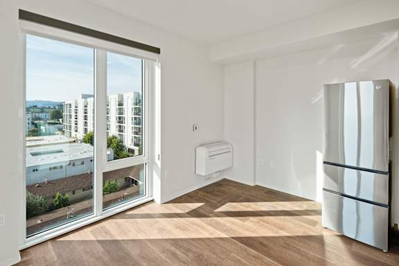A modern kitchen with a white refrigerator and a view of the city through the sliding glass doors.