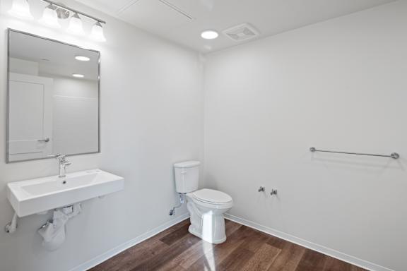 A white bathroom with a toilet, sink, and mirror.