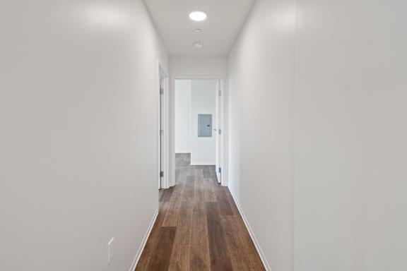 A long hallway with wood floors and white walls.