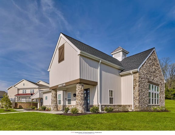 a white barn style home with a stone facade and a lawn