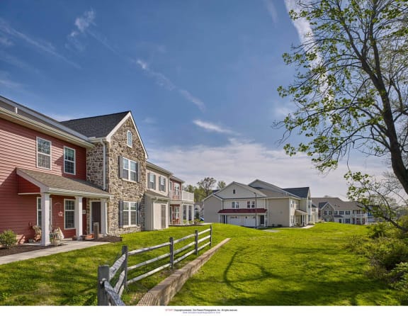 a row of houses on a hill with a green lawn and a fence