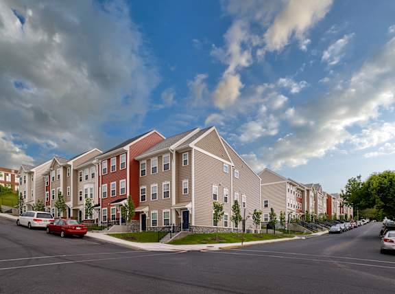 a row of townhomes with cars parked on the side of the road