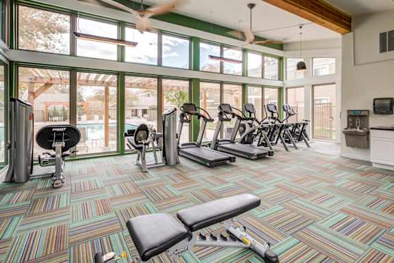 A gym with a variety of equipment including treadmills, weights, and exercise bikes.