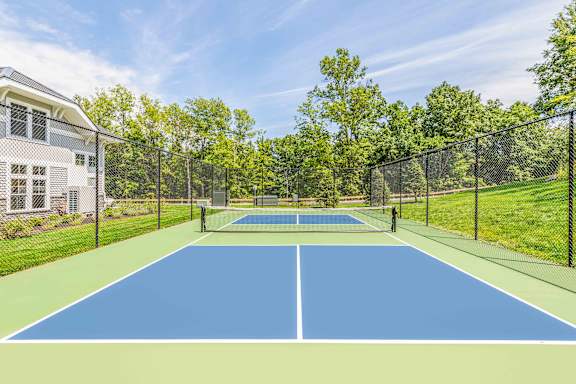 A tennis court is surrounded by a fence and trees.