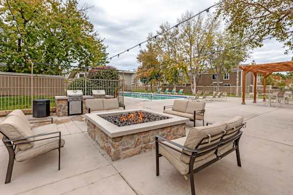 A patio with a fire pit and chairs.