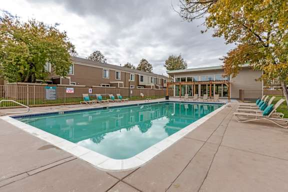 A swimming pool surrounded by a concrete floor and a wooden fence.