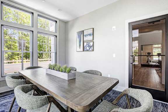 A dining room with a long wooden table and grey chairs.