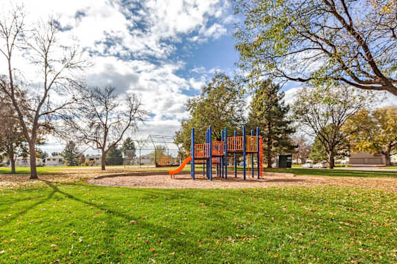 A playground with a slide and a green lawn.