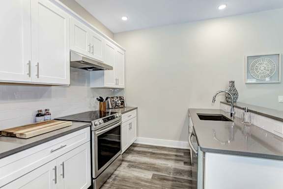 A kitchen with white cabinets and a wooden cutting board on the counter.