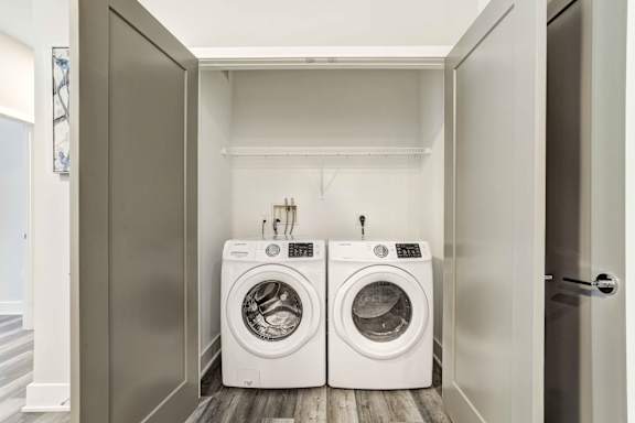 A pair of white front load washing machines in a small laundry room.