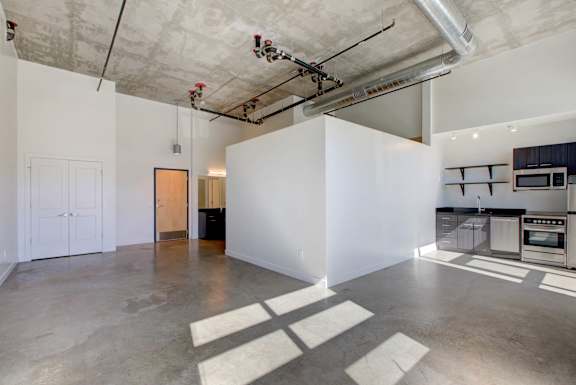 A large empty room with a kitchen area in the back at RiDE at RiNo Apartments, Denver 80216