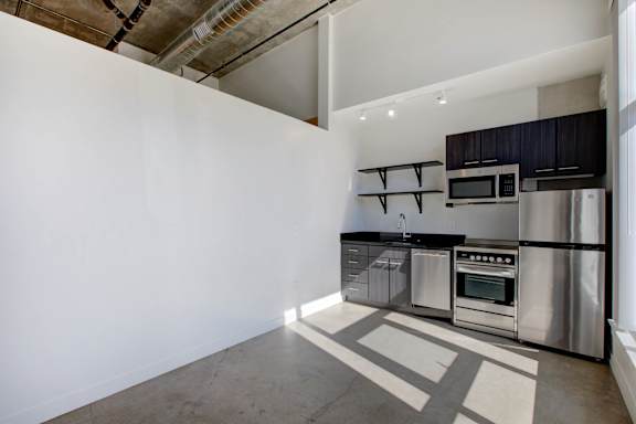 A modern kitchen with stainless steel appliances and a white wall at RiDE at RiNo Apartments, Denver, CO, 80216