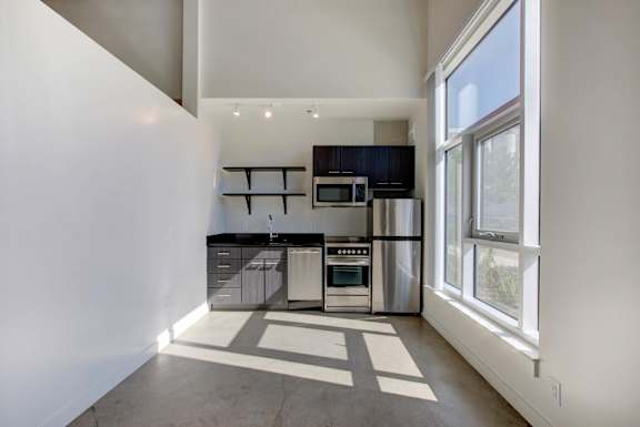 A kitchen with white walls and a black fridge at RiDE at RiNo Apartments, Denver, Colorado