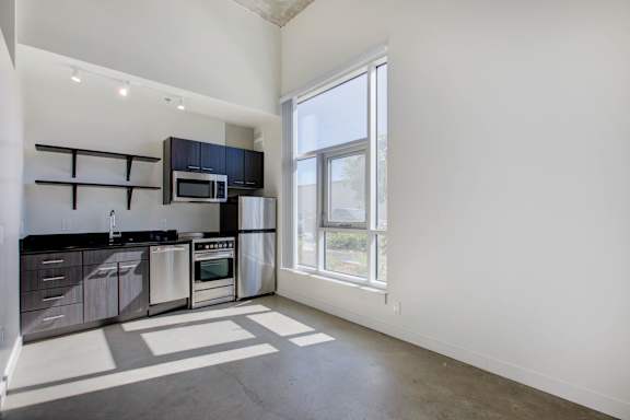A kitchen with black cabinets and stainless steel appliances at RiDE at RiNo Apartments, Denver, CO