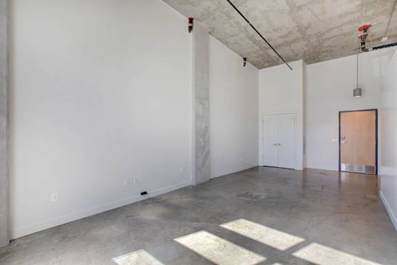 A large empty room with a concrete floor and white walls at RiDE at RiNo Apartments, Denver
