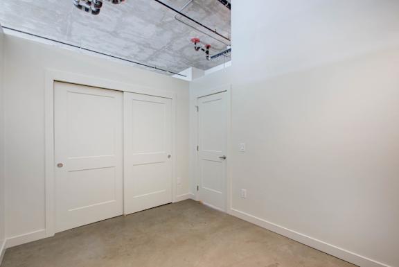 A room with white walls and a concrete ceiling with a skylight at RiDE at RiNo Apartments, Denver, Colorado