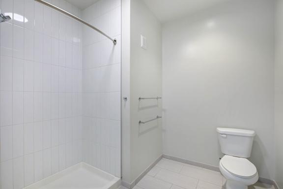 A white toilet sits next to a walk-in shower at RiDE at RiNo Apartments, Colorado
