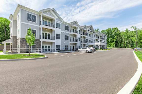 A large white apartment building with a parking lot in front.