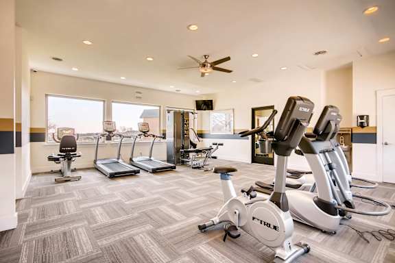 A gym with a variety of exercise equipment including treadmills, stationary bikes, and elliptical machines at Mountain Vista Apartments, Colorado