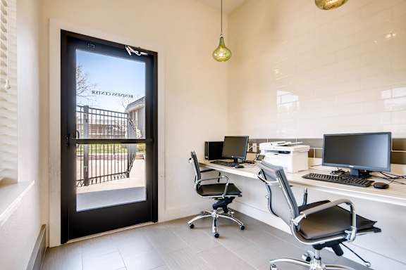 A modern office with a view of a black gate and trees outside at Mountain Vista Apartments, Lakewood, 80228