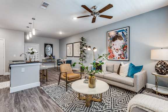 A living room with a white couch, a coffee table, and a ceiling fan.
