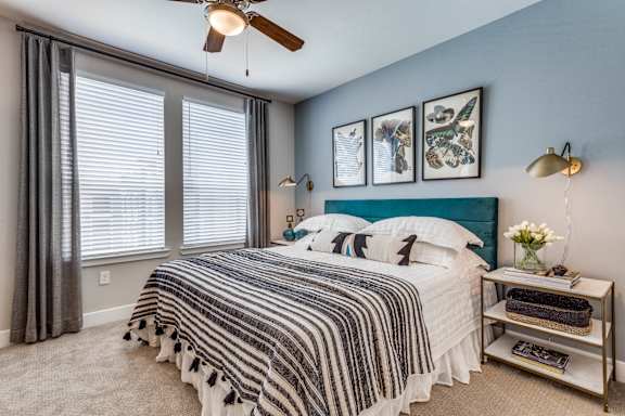 A bedroom with a bed, a nightstand, and a ceiling fan.