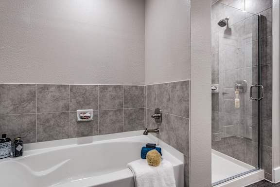 A bathroom with a white tub and grey tiles.