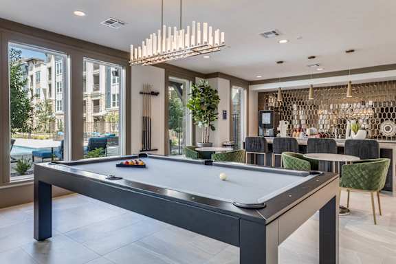 A pool table in a room with a view of a building outside the window.