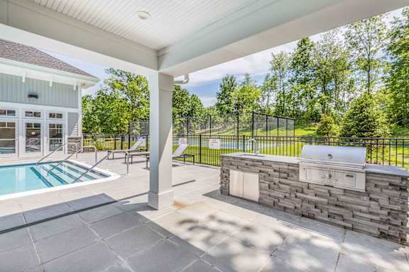A patio with a pool and a stone wall.